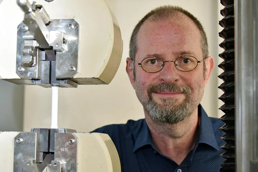 Prof. Dr. Frank A. Müller, Professur für Oberflächen und Grenzflächentechnologie am Otto-Schott-Institut für Materialforschung (OSIM) der Friedrich-Schiller-Universität Jena, aufgenommen am 29.05.2020. Im Bild links ist eine Universalprüfmaschine zur Charakterisierung der Bruchfestigkeit von Werkstoffen zu sehen. (Foto: Anne Günther/FSU)