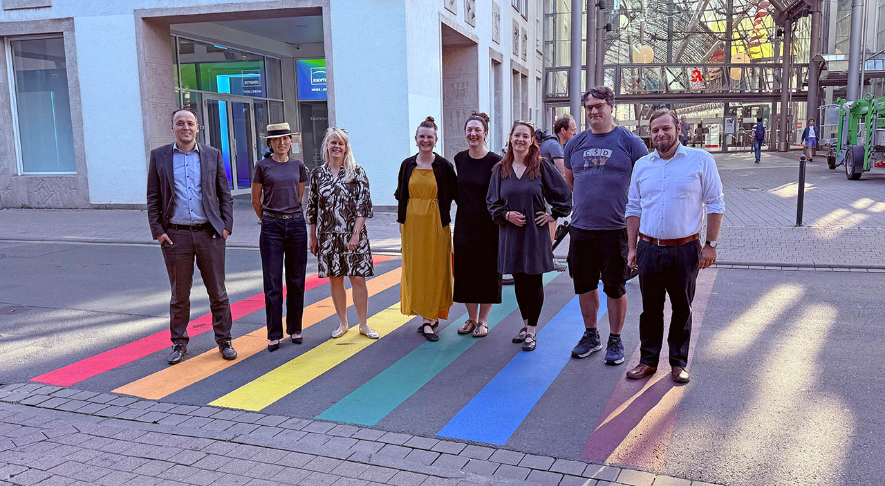 Buntes Zeichen mitten in der Stadt. Eine bunte Gesellschaft eröffnete den Regenbogenweg an der GoetheGalerie – in der Mitte die Initiatorin Petra Teufel und Kathleen Lützkendorf, Jenaer Dezernentin für Soziales, Gesundheit, Zuwanderung und Klima© Stadt Jena / Kristian Philler