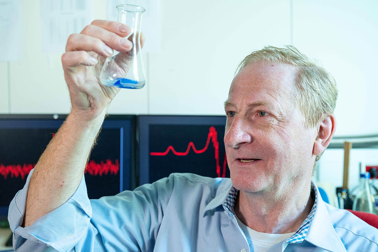 Projektleiter Prof. Dr. Winfried Plass vom Institut für Anorganische und Analytische Chemie der Universität Jena betrachtet den Kristall einer Kupferverbindung, mit der das Team seine Untersuchungen zu Spin-Zuständen in Molekülen durchgeführt hat (Foto: Nicole Nerger/Universität Jena)