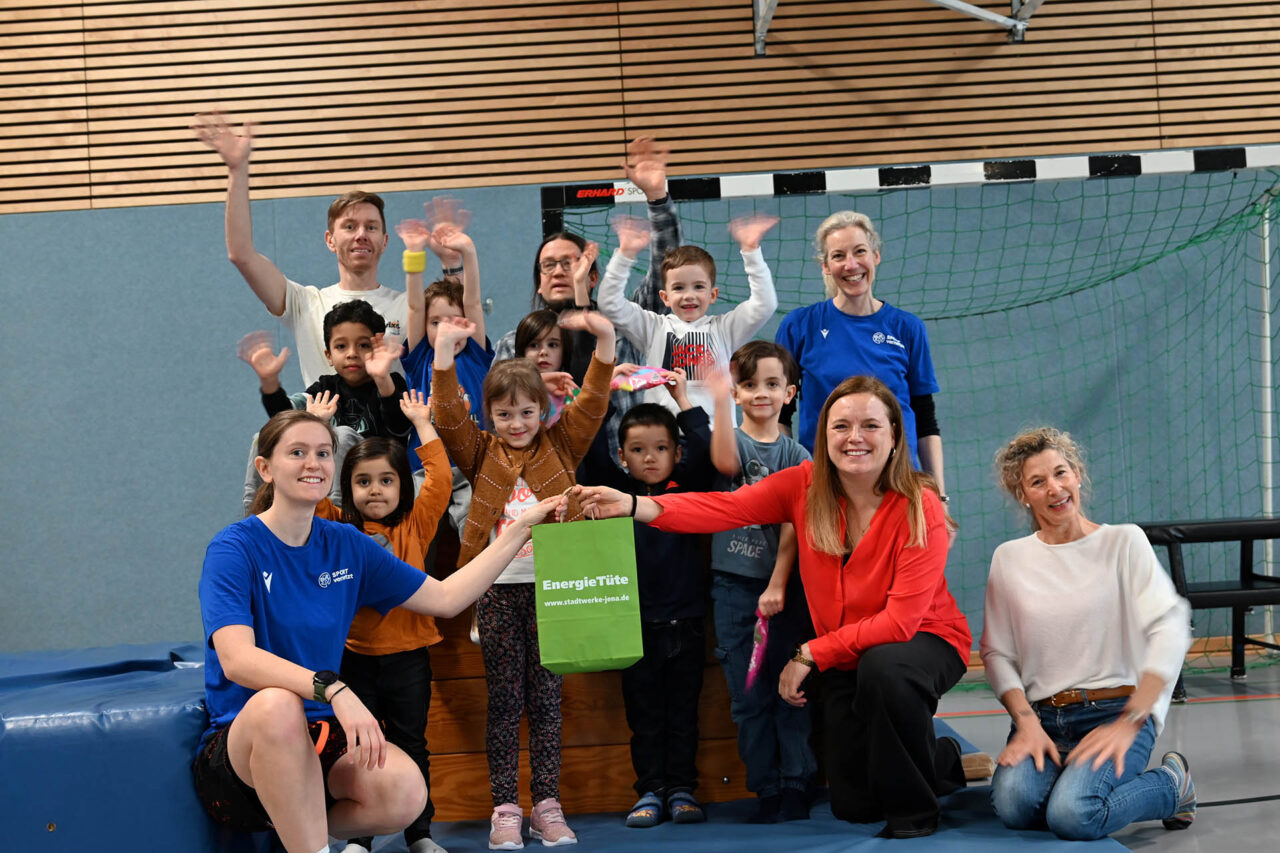 Spendenübergabe in der Turnhalle Winzerla: Vorne links Friederike Fischer (Verein SPORT VERNETZT), Tina Schnabel und Alice Grosse (beide Stadtwerke Jena) gemeinsam mit Kindern der Kita BiLLY sowie (hinten v. l. n. r.) Michael Burkhardt-Wilhelm (Kita BILLY), Markus Mess (Stadtteilbüro Winzerla) und Vanessa Hirsch (Verein SPORT VERNETZT). Foto: Stadtwerke Jena, Karoline Herzog Spendenübergabe in der Turnhalle Winzerla: Vorne links Friederike Fischer (Verein SPORT VERNETZT), Tina Schnabel und Alice Grosse (beide Stadtwerke Jena) gemeinsam mit Kindern der Kita BiLLY sowie (hinten v. l. n. r.) Michael Burkhardt-Wilhelm (Kita BILLY), Markus Mess (Stadtteilbüro Winzerla) und Vanessa Hirsch (Verein SPORT VERNETZT). Foto: Stadtwerke Jena, Karoline Herzog